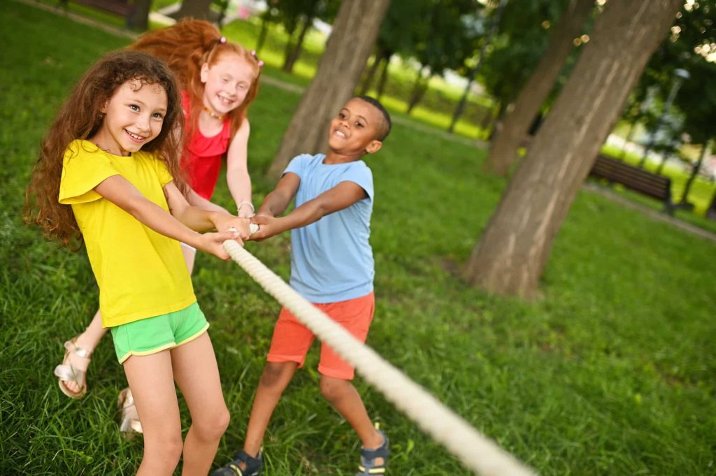 a-group-of-children-compete-in-a-tug-of-war-in-the-open-air-against-the-background-of-grass-and-park.jpg